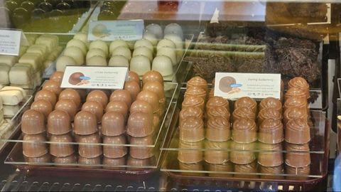 A selection of chocolate pralines in various shapes and colors. The pralines are neatly presented in display cases and invite tasting.