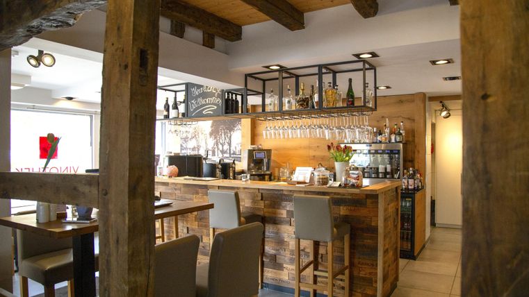 Een gezellige bar met een houten balie en moderne stoelen. De inrichting combineert rustieke charme met een uitnodigende sfeer.