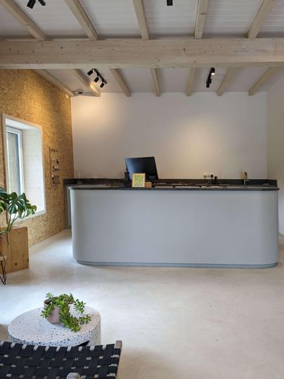Un espace d'accueil moderne avec un sol clair et de grandes fenêtres. Le comptoir est conçu de manière simple et accueillante.