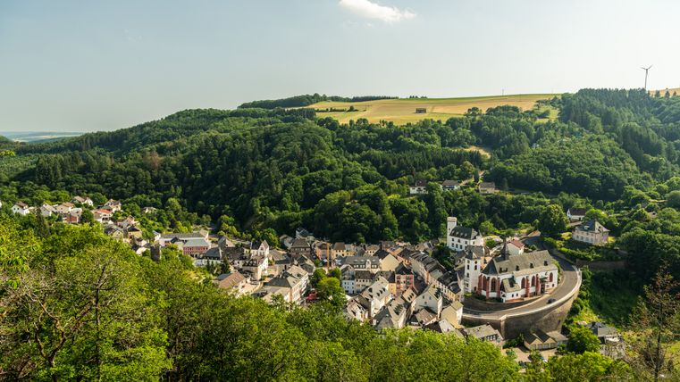 Vue panoramique sur Neuerburg avec son église et les forêts environnantes.