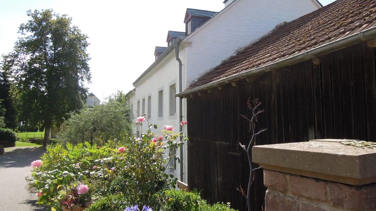 Farmhouse with garden in Dahlem, sunny day.