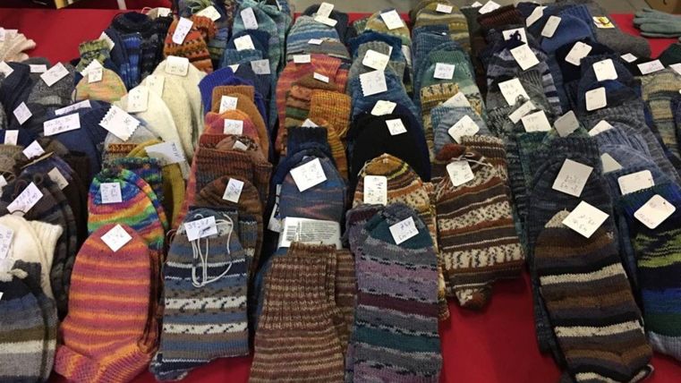 Une table pleine de chaussettes colorées aux différents motifs et couleurs. Les chaussettes sont étiquetées et soigneusement rangées.