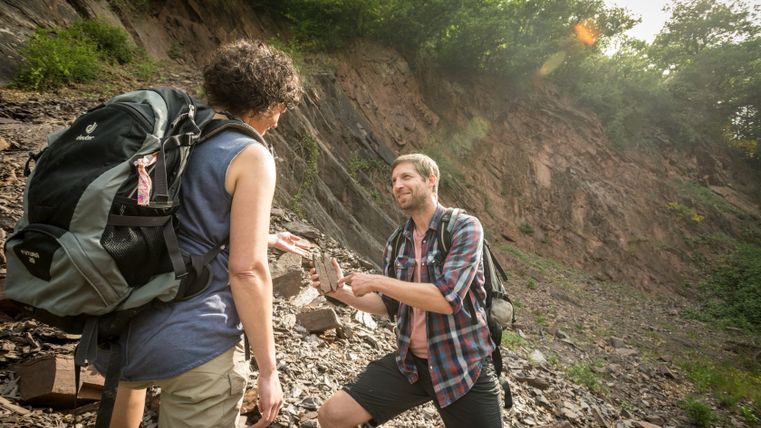 Deux personnes lors d'une excursion géologique, l'une montre une pierre.