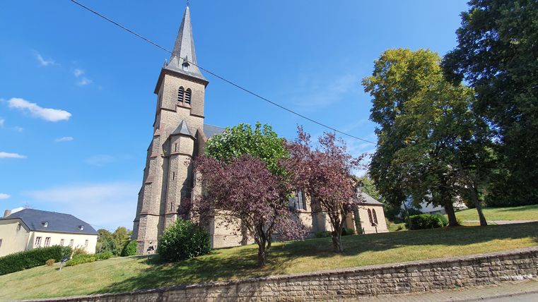 St Bartholomew's parochiekerk met spitse toren en bomen op de voorgrond.