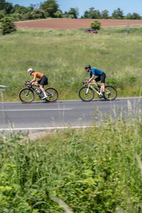 Two cyclists on a country road in a rural setting.