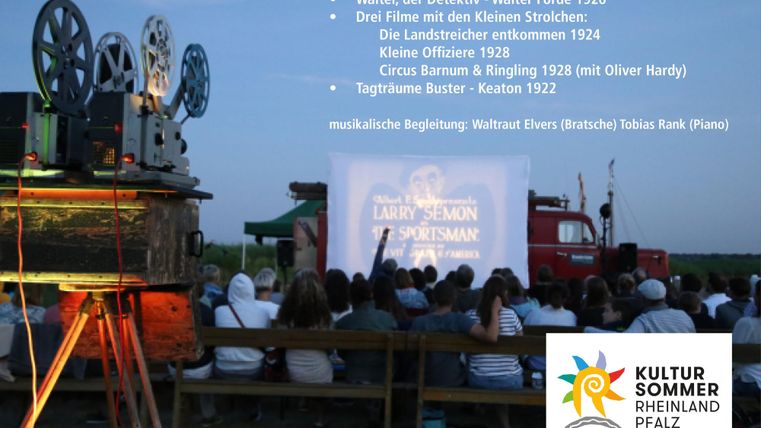 An open-air cinema with a film projection projector and a seated crowd of viewers. In the background, there are trees and a truck, while old films are being shown on a screen.