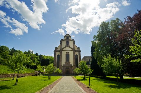 Frontansicht des Klosters Himmerod mit blauem Himmel und grüner Umgebung.