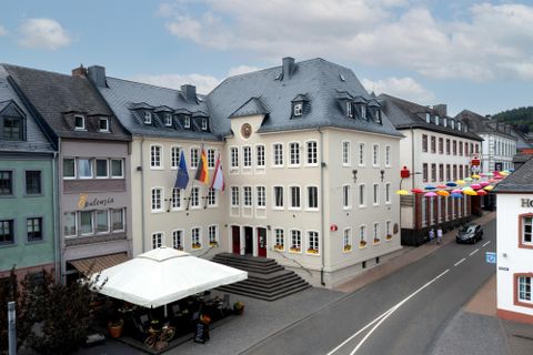 Un joli bâtiment avec plusieurs drapeaux devant un ciel dégagé. La rue est calme et un auvent invite à s'attarder.