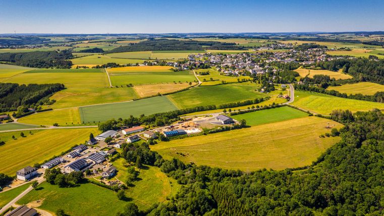 A group of eight people is sitting on a sofa in an indoor setting. They are wearing colorful clothing and funny accessories, indicating a cheerful, casual atmosphere.