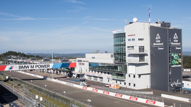 Un circuit de course avec des bâtiments modernes et un ciel bleu clair. L'environnement est idéal pour les événements de sport automobile.