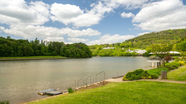 Bitburg reservoir with green surroundings and cloudy sky.