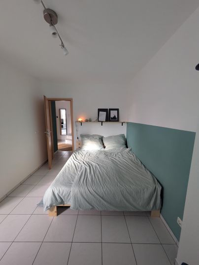 Een moderne slaapkamer met een tweepersoonsbed en lichte muren. De ruimte oogt uitnodigend en goed gestructureerd.