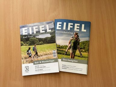 Auf einem Tisch liegen zwei Prospekte aus der Eifel