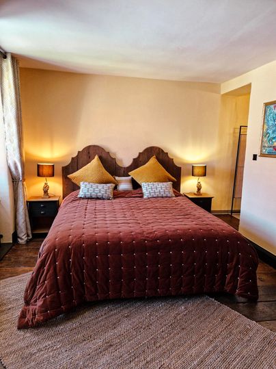 A cozy bedroom with a large brown bed and yellow pillows. Soft light from the bedside lamps creates a relaxed atmosphere.