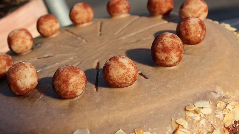 Een heerlijke taart met een gladde oppervlakte en decoratieve chocoladebollen. Amandelen omringen de basis van de taart.