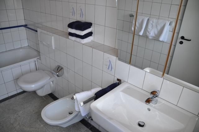 Ein modernes Badezimmer mit weißen Fliesen. Es sind Handtücher und Pflegeprodukte ordentlich arrangiert.