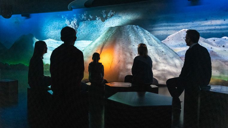 Mensen zitten voor een verlichte vulkaanprojectie in de Lava Dome Mendig.