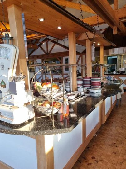 Ein einladendes Buffet mit frischen Früchten und Geschirr steht in einem gemütlichen Restaurant. Das Holzinterieur sorgt für eine warme Atmosphäre.