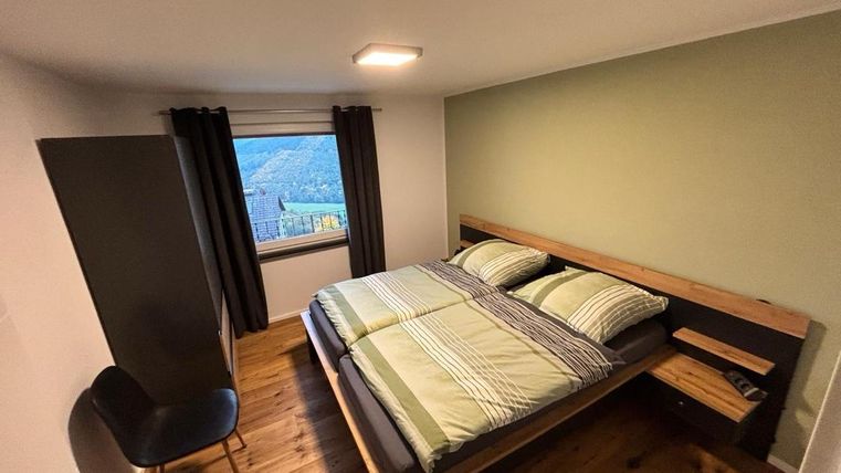 Een modern slaapkamer met een groot tweepersoonsbed en een gezellige zithoek. Het raam biedt uitzicht op het landschap.