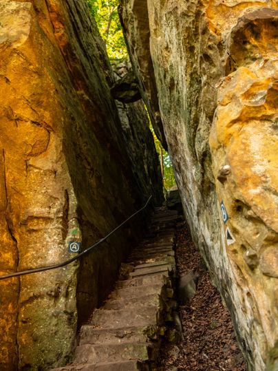 Un sentier étroit et rocailleux traverse une gorge rocheuse étroite aux parois abruptes.