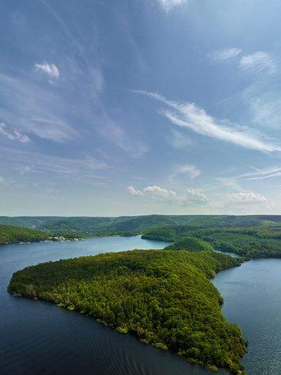 Blick auf einen Stausee und waldige Hügel