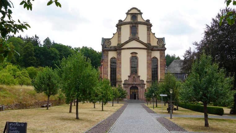 An impressive church stands at the end of a cobbled path. Surrounded by trees and green spaces, it radiates a calm atmosphere.