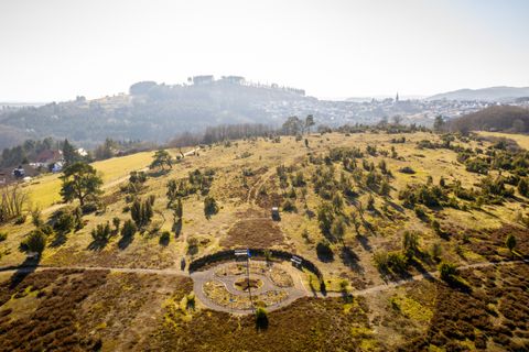 Landschaft mit Hügeln, Bäumen und einem kleinen Labyrinth auf einem Wanderweg.