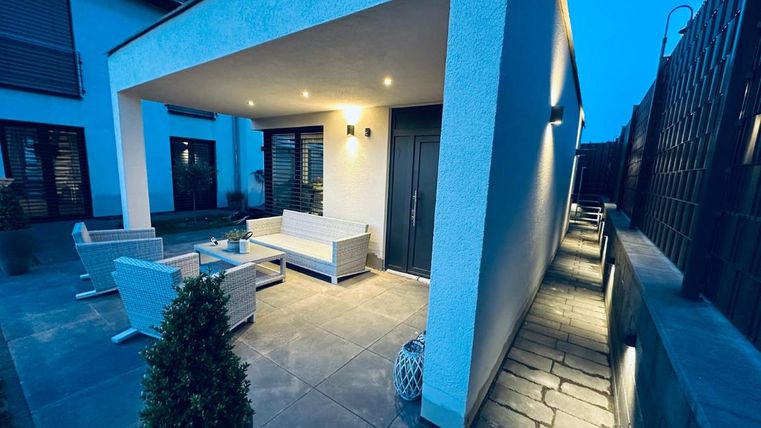 A modern outdoor seating area with a bright terrace and stylish furniture. The space is softly lit and invites relaxation.