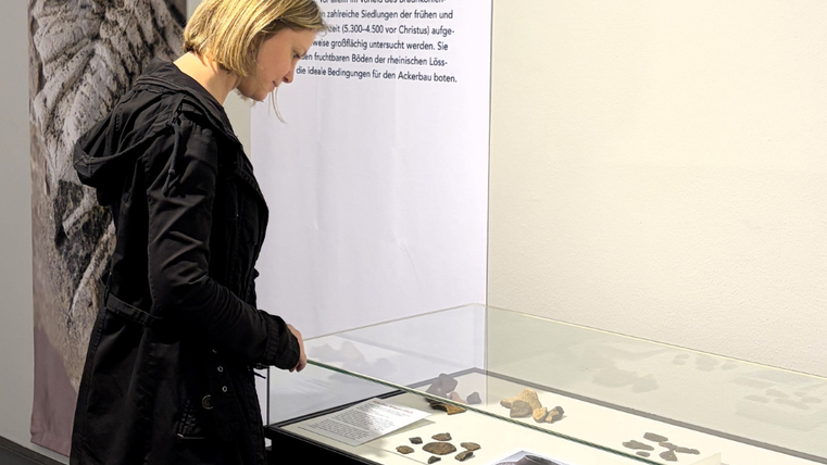 Eine Frau schaut auf eine Tischvitrine in einer Ausstellung.
