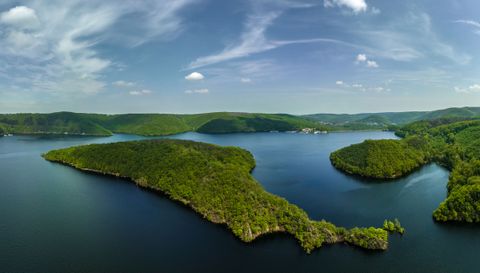 Blick auf einen See umgeben von Hügeln mit Wald
