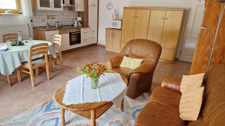 Woon- en eetkamer met een bruine bank en een keuken op de achtergrond