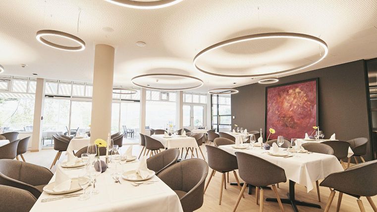 Een modern restaurant met elegante tafels en stoelen. Het licht is helder en de muren zijn smaakvol versierd.