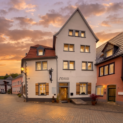 A charming, historic building on a picturesque street. In the background, the sky glows in warm colors during sunset.