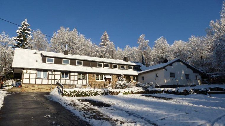 Een met sneeuw bedekt gebouw in een winterlandschap. Bomen zijn bedekt met sneeuw en de lucht is helder en blauw.