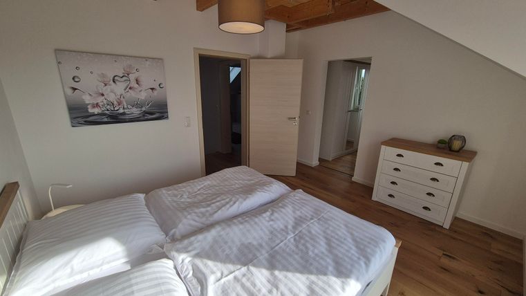 Une chambre moderne avec deux lits et un sol en bois. Les murs sont peints en clair et une peinture est accrochée au mur.