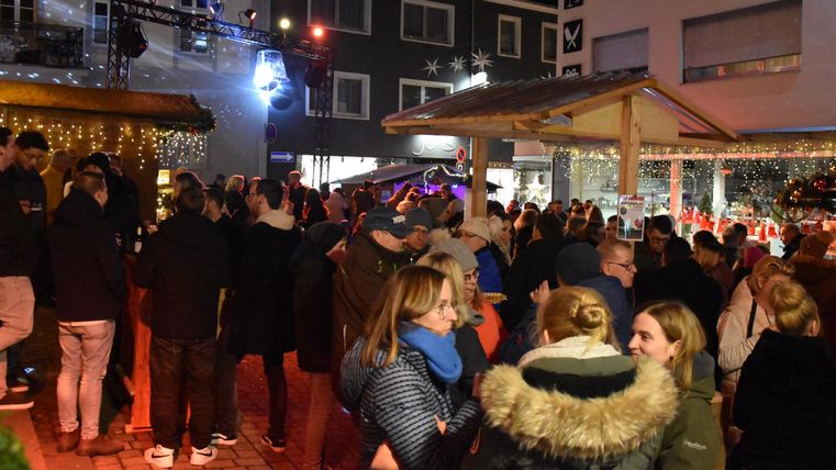 A lively crowd at a festive market at night. The atmosphere is cheerful and inviting.