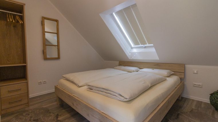 Une chambre confortable avec un grand lit double et des meubles en bois. Une fenêtre de toit permet de laisser entrer beaucoup de lumière naturelle.