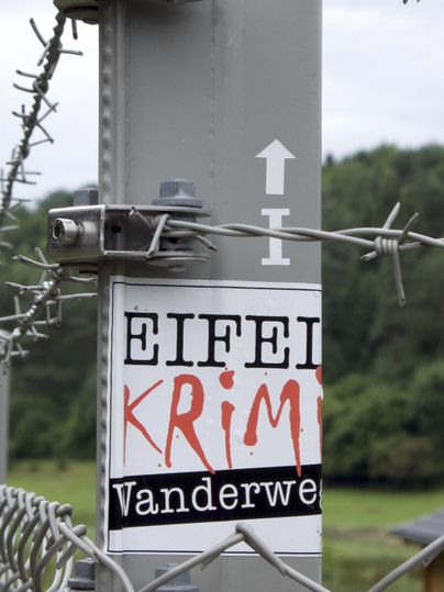 The logo of the Eifel Kirmi hiking trail on a lamp post