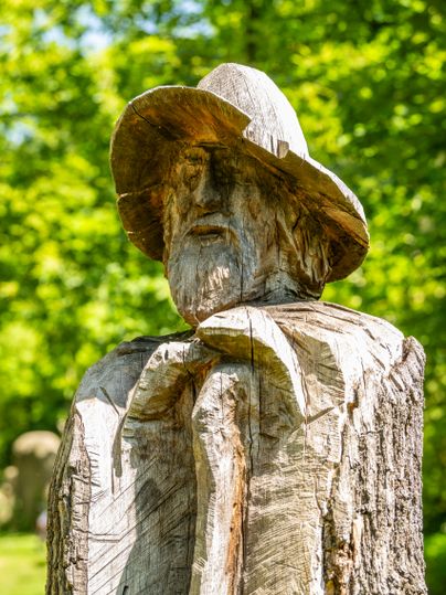 Portrait view of a sculpture of a man with hat and stick