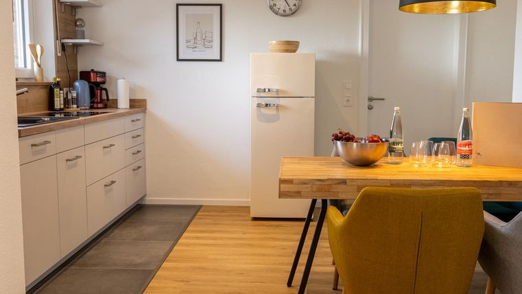 Een moderne keuken met een eettafel en gele stoelen. De inrichting is licht en gezellig, met een combinatie van houten en metalen accenten.