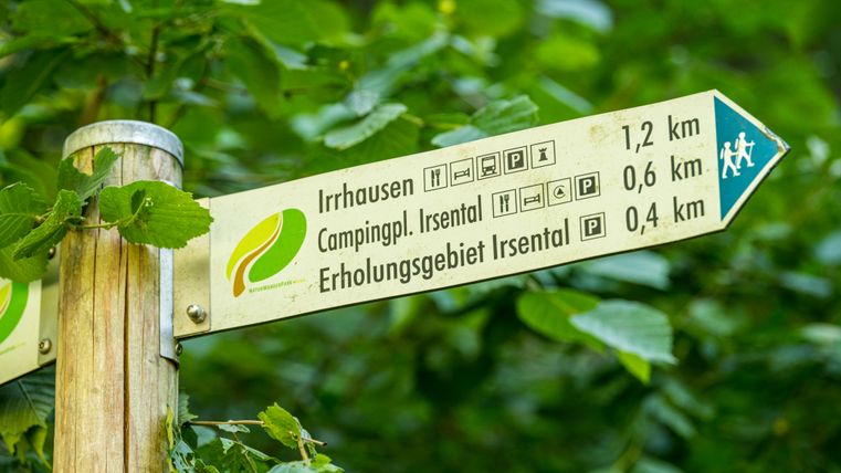Auf einem Schild in Pfeil-Form sind die Entfernungen zum nächsten Wanderziel angegeben
