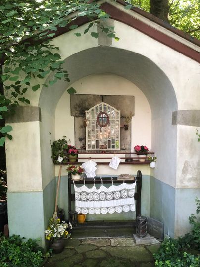 Une petite chapelle avec une entrée en arc et des fleurs. La pièce est décorée avec une baie vitrée et une nappe.