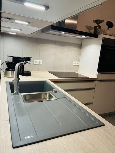 Een moderne keuken met een elegante gootsteen en kookplaat. Het interieur is licht en functioneel ingericht.