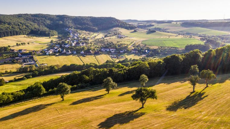 Paysage dans la vallée de l'Enz avec des champs, des arbres et un village en arrière-plan.