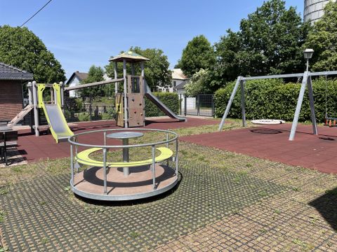 Frontalansicht auf die Spielgeräte, Kletterturm, Schaukel und Karussell.