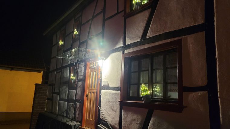 Ein historisches Fachwerkhaus bei Nacht mit warmem Licht an der Eingangstür. Die Fenster sind sanft beleuchtet und verleihen dem Gebäude einen einladenden Charme.