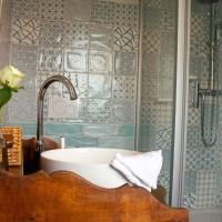 A modern bathroom with an elegant washbasin and artistic tiles. In the background, a shower and floral decor can be seen.