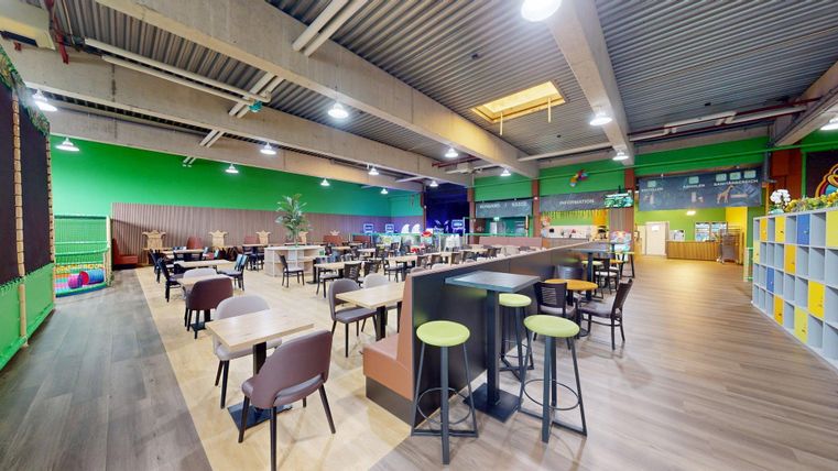 Een modern restaurant met kleurrijke muren en vele tafels. De ruimte is licht en uitnodigend, ideaal voor gezellige ontmoetingen.