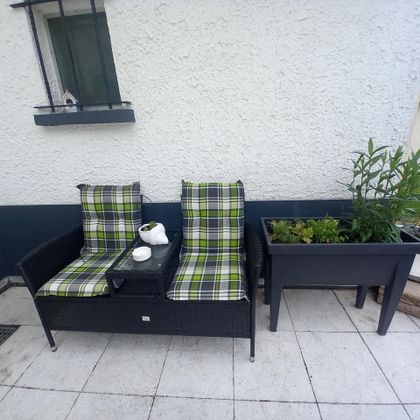 Een gezellige zithoek met twee fauteuils en een klein tafeltje. Naast de bank staat een plantenbak met groene planten.