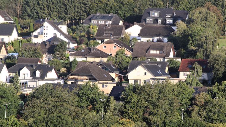 Une zone résidentielle calme avec différentes maisons et beaucoup de verdure. Des arbres entourent les bâtiments et créent une atmosphère agréable.